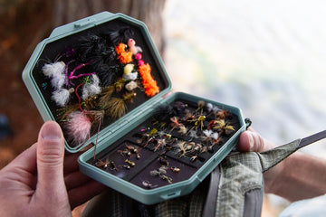 Close up of an Atollas 1GO Fly Box opened up with assorted flies displayed while outdoors