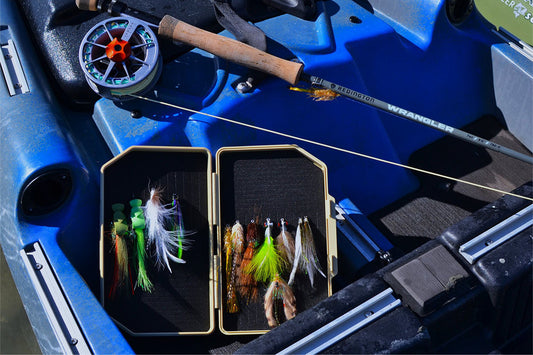 Atollas 2GO Fly Box with flies attached in it sitting in a blue kayak with fly rod in background