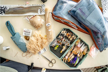 Overhead view of an Atollas 2GO Fly Box opened with assorted saltwater flies and fly tying material