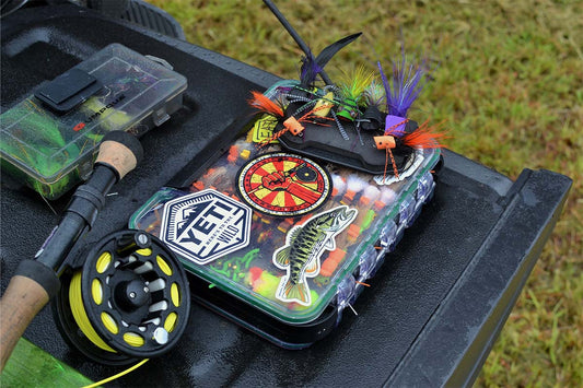 Atollas Fly Caddy XL clippable fly patch with popper flies attached top of it with fly rod and truck bed as background