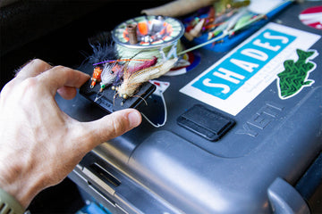 Close up of a fly angler's hand holding a Fly Caddy clippable fly patch getting ready to clip it into a docking station adhered to a hard case
