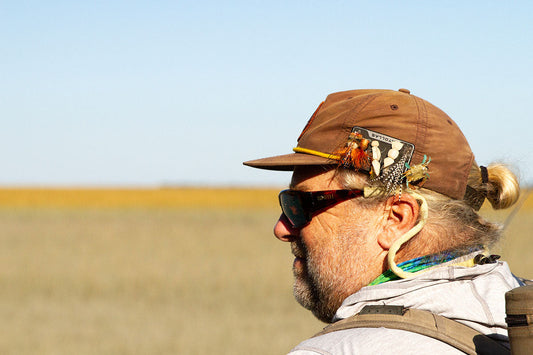 Fly angler with Atollas Fly Caddy clippable fly patch attached to his hat with marsh in background