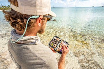 Fly angler on a flat in Exuma looking out into the shallows with 2GO Fly Box in hand