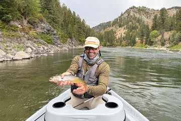 Fly fisherman holding a cutthroat trout on snake river in Wyoming
