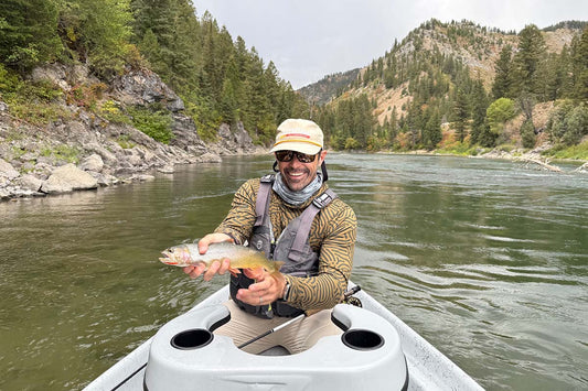 Fly fisherman holding a cutthroat trout on snake river in Wyoming