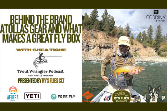 Picture of Atollas founder Shea Tighe on the bow of a river raft holding a trout with mountains and trees in background.