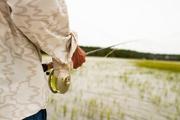 Close up of a fly rod being held by a fly fisherman in a flooded grass flat outside