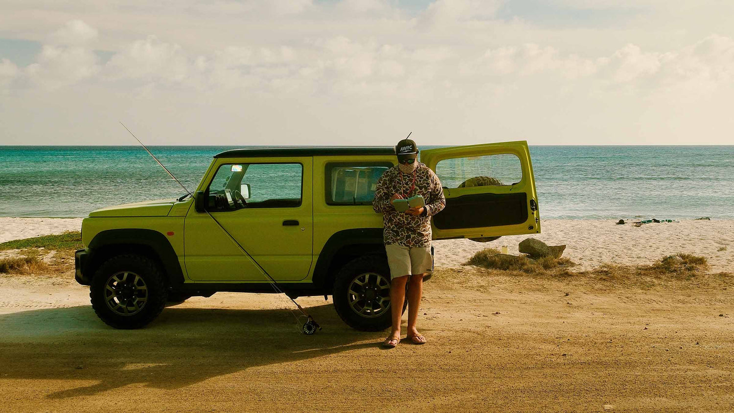 Atollas Ambassador Lucas Armstrong holding an Atollas 2GO Fly Box by his car at the beach in Aruba outside.