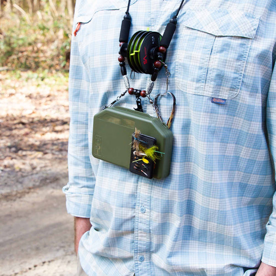 Fly Angler with a lanyard around his neck clipped to an olive Atollas 1GO Fly box outdoors