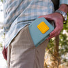 Fly angler pulling a green Atollas 1GO Fly Box out of his pants pocket outdoors