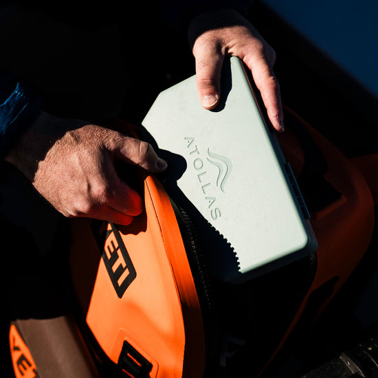 Person holding a green Atollas 2GO Fly Box and packing it into an orange YETI back pack