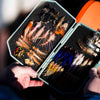 An Atollas 2GO Fly Box opened in hand displaying various saltwater flies with a blurred background