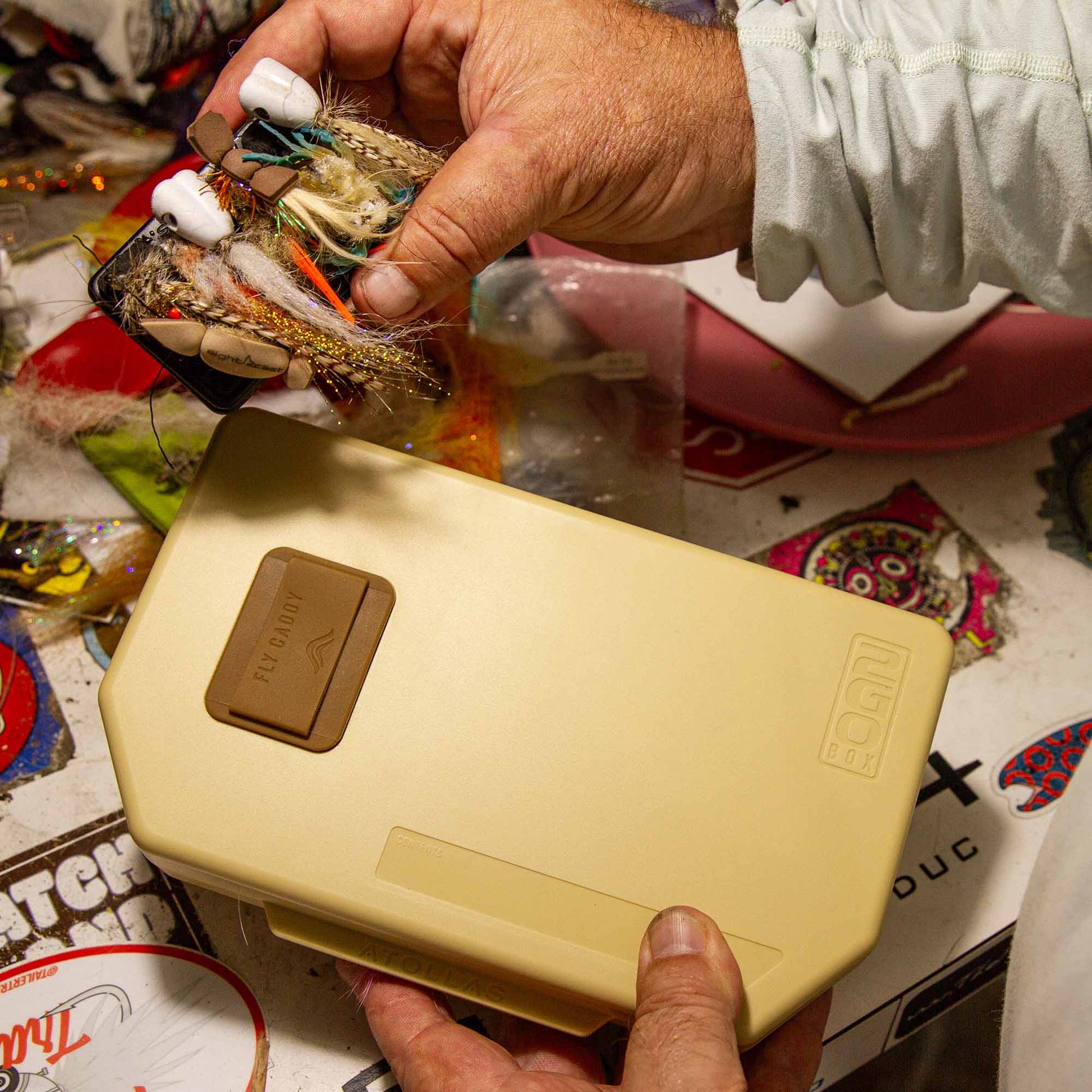 Person holding a Fly Caddy clippable fly patch getting ready to clip it into the docking station of a sand colored Atollas 2GO Fly Box