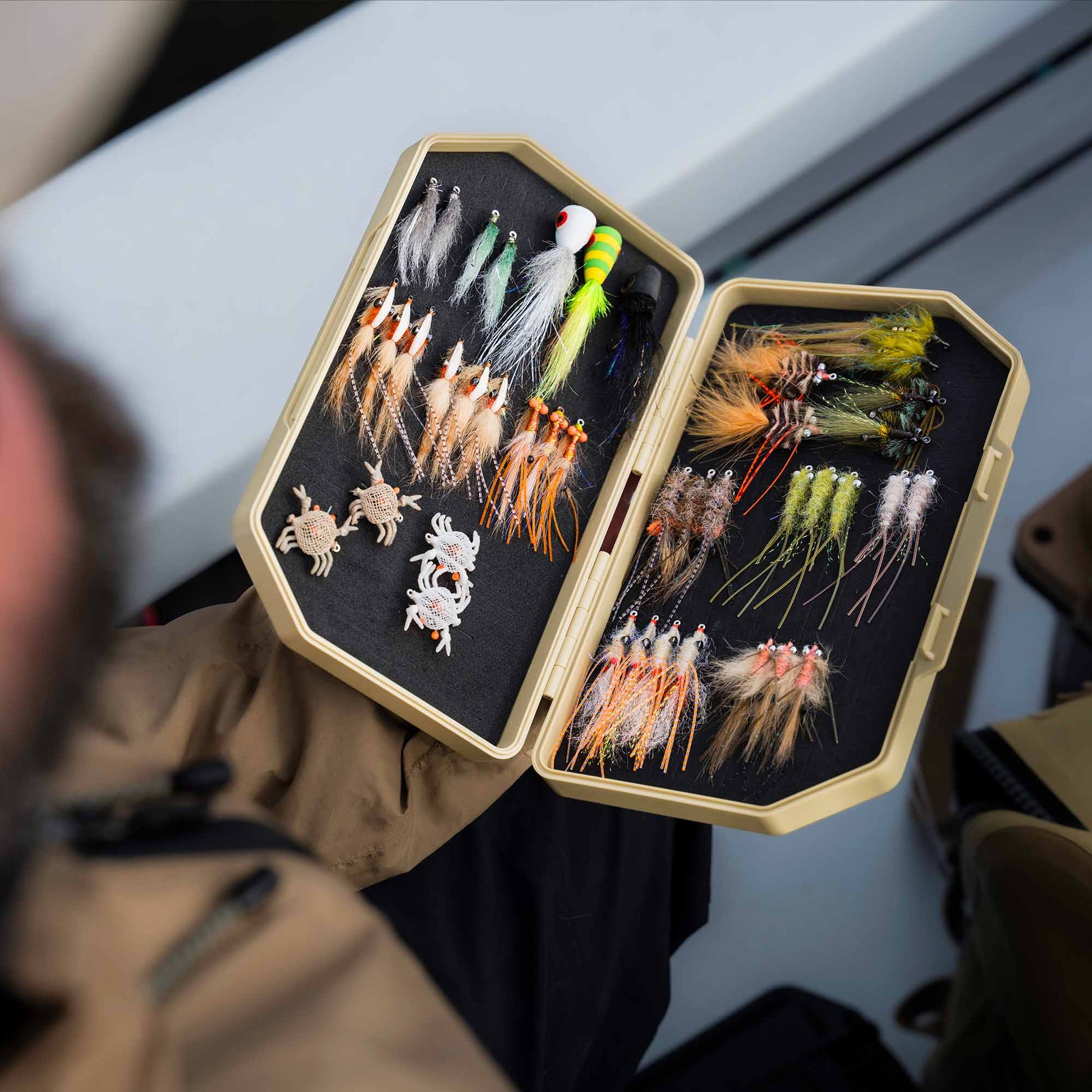 Fly Angler with an open sand colored 2GO Fly Box with assorted saltwater flies displayed in the box, while in boat