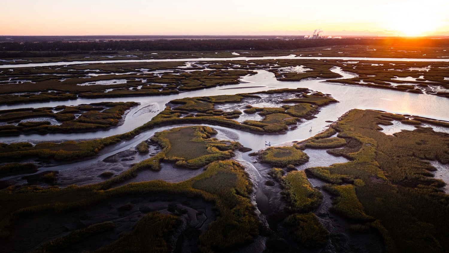 Aerial view of a marshy landscape with winding rivers at sunset