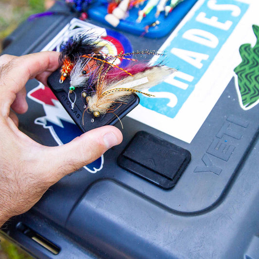 Hand holding an Atollas Fly Caddy fly patch and clipping it to a docking station attached to a YETI loadout box