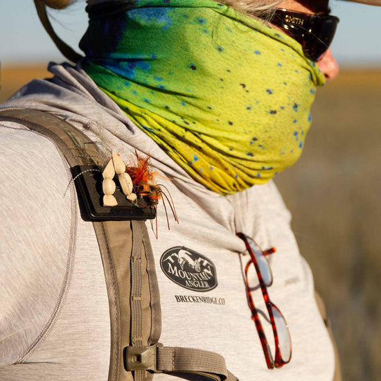 Fly angler wearing a green bandana, glasses, and a backpack with an Atollas Fly Caddy clippable fly patch clipped onto the shoulder strap