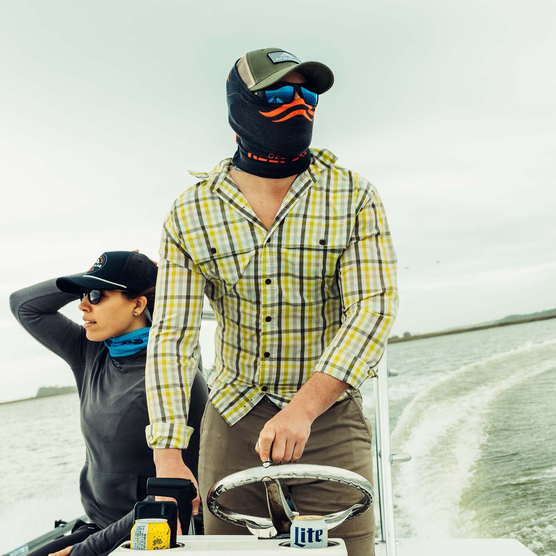 Two fly anglers on a boat wearing hats and Atollas sun mask with a neutral background