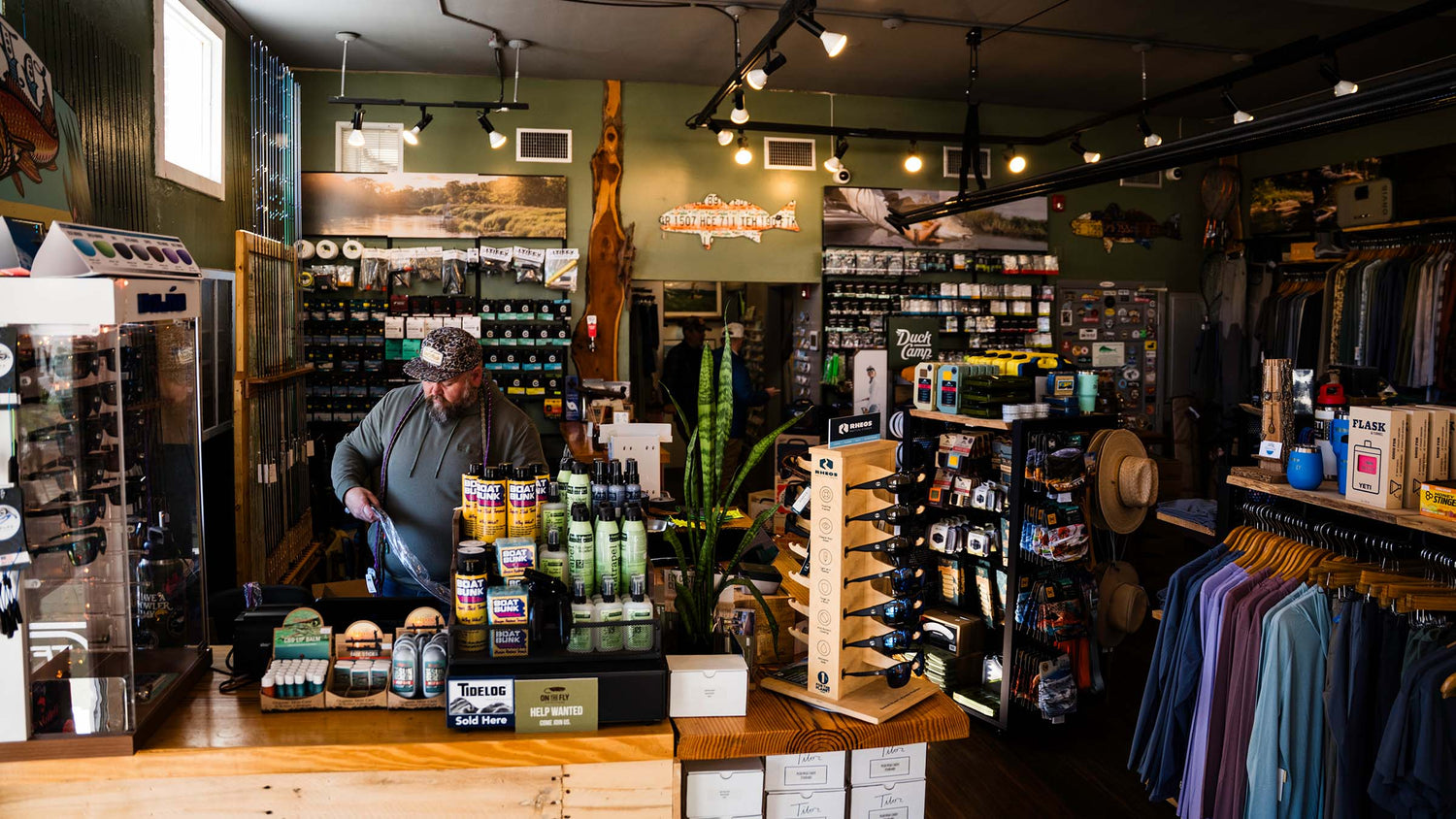Interior of a fly fishing store with various products on shelves and a person working behind the counter