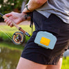 Fly angler holding a fly fishing rod with a green Atollas Micro Fly Box attached to their shorts outdoors