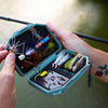 An Atollas Micro Fly Box open with various flies held by a fly angler outdoors