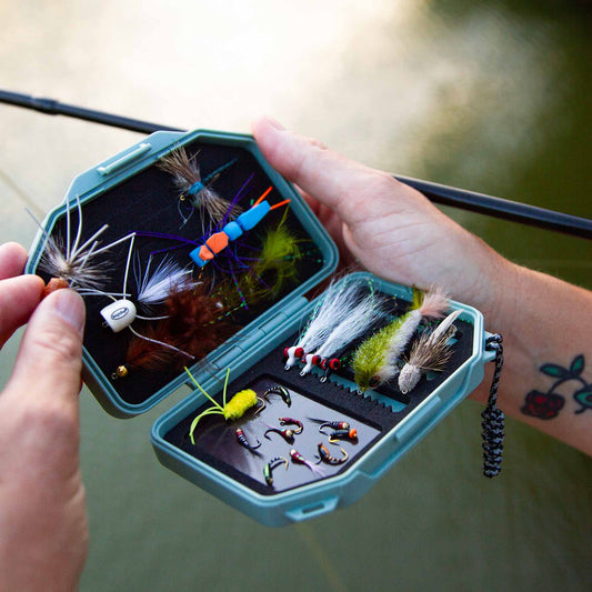 An Atollas Micro Fly Box open with various flies held by a fly angler outdoors