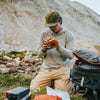 Fly angler in outdoor setting using an Atollas Micro Fly Box with mountains in the background