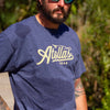 Fly angler wearing a blue t-shirt with 'Atollas Gear' logo outdoors