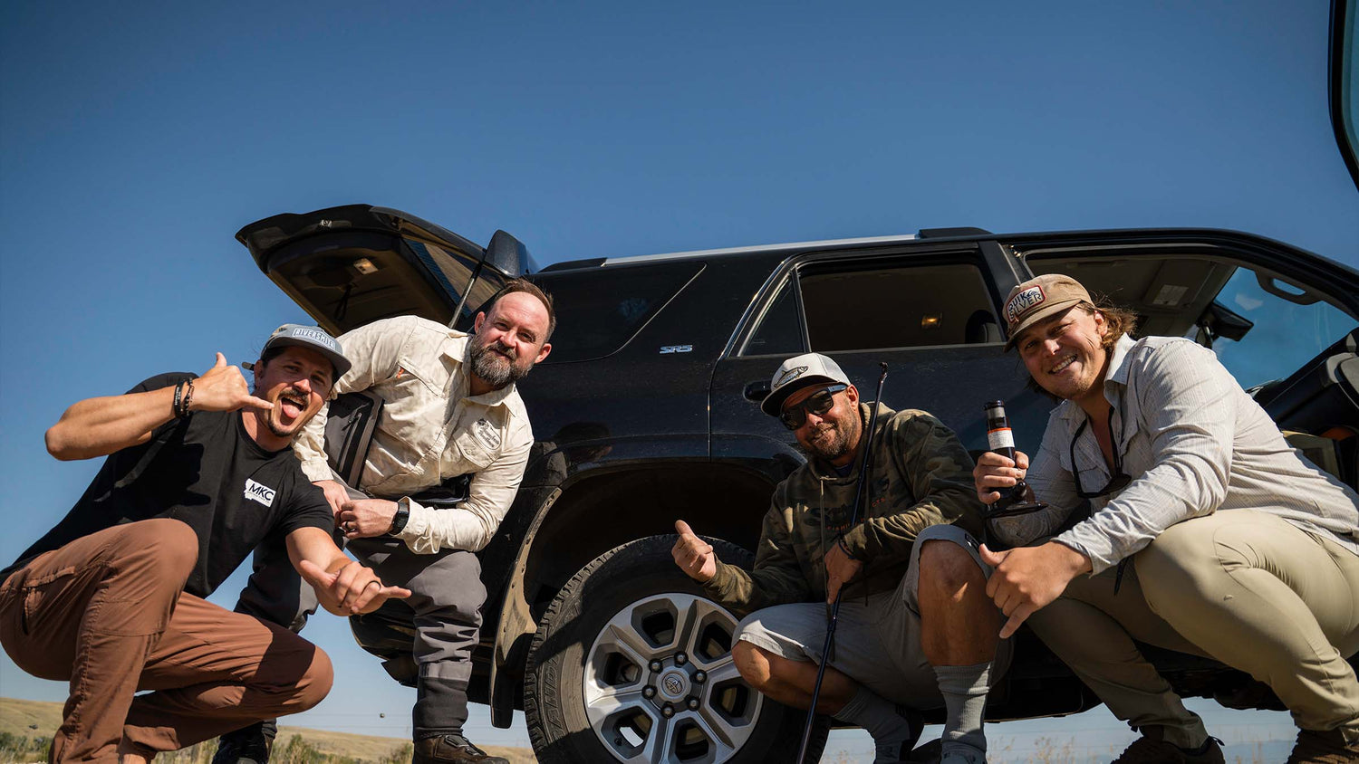 Four fly anglers posing for a picture after a fly fishing session in Bozeman Montana outside in front of an SUV